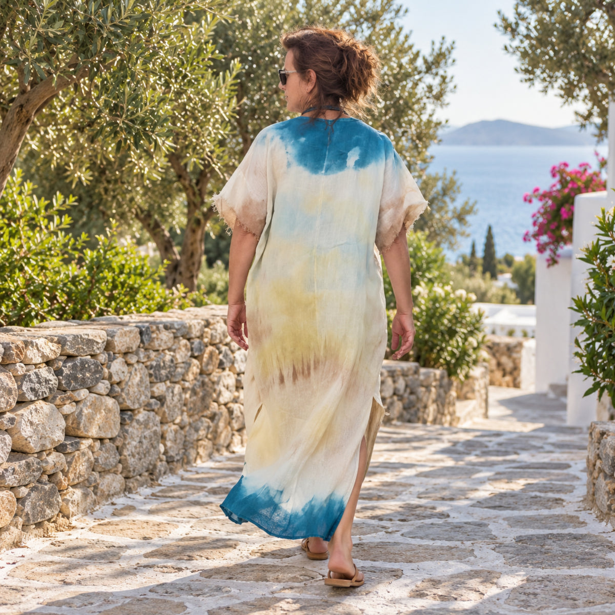 Πίσω όψη του χειροποίητου λινού καφτανιού Shibori Ανθεία, φορεμένου σε φυσικό νησιώτικο περιβάλλον.
